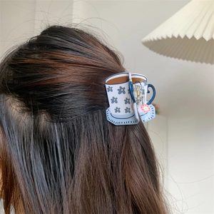 Detail of coffee cup shaped hair claw clip with blue floral pattern in hair