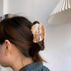 Detailed view of sea shell acetate hair claw clip with marble texture on braided hair