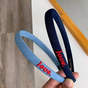 Detailed view of handmade blue fabric headbands with red love embroidery and interior labels