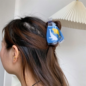 Close-up of a sky blue ocean-inspired large hair claw clip worn on a female model