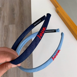 Close-up of slim blue headbands featuring red 'love.' embroidery and handmade labels