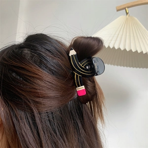 Detailed close-up of a creative pencil-shaped acetate hair claw clip on brunette wavy hair