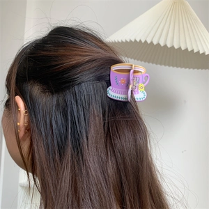 Detailed view of a purple floral tea cup shaped hair claw clip styled on a brown ponytail