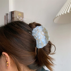 Detail of blue nautilus shell hair claw clip with gold lines and white polka dots on hair