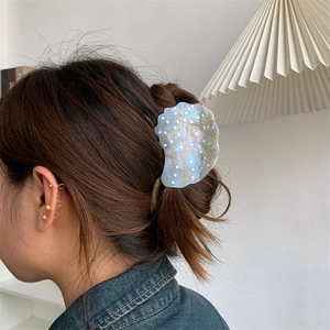 Detail of seashell acetate hair claw clip with golden spiral texture and white dots