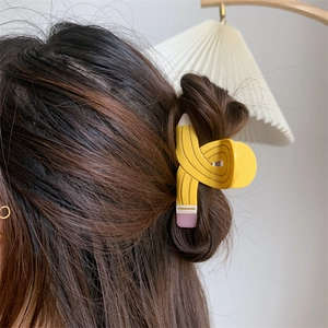 Close-up of a creative pencil-shaped acetate hair claw clip worn on a half-up hairstyle