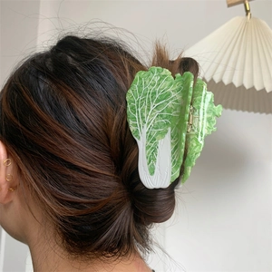 Detailed view of creative cabbage-shaped acetate hair claw clip worn on hair with green leaves