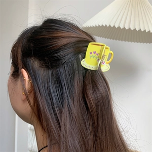 Detailed view of yellow coffee cup shaped hair claw with purple tulip floral patterns