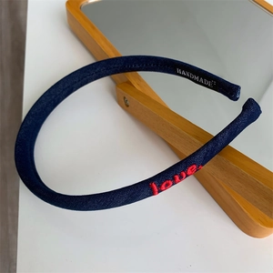 Close-up of navy denim headband featuring red love embroidery and handmade label detail