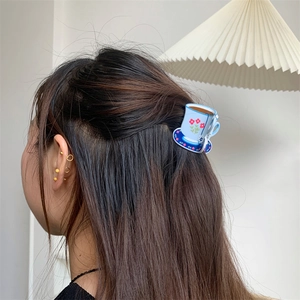 Creative tea cup acrylic hair claw with blue floral patterns on long brown hair
