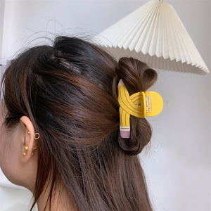 Creative yellow pencil shaped hair claw clip styled on a woman's half-up hairstyle