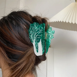 Detailed view of creative green cabbage hair claw clip styling on long brown hair