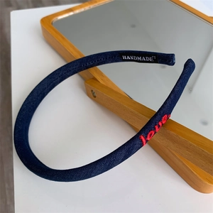 Detail of navy blue fabric headband featuring red love embroidery and handmade label