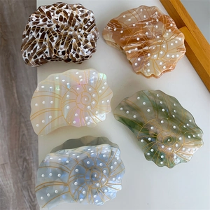 Detailed top view of five conch-shaped acetate hair claws in various marble textures