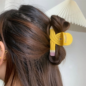 Creative yellow pencil shaped acetate hair claw clip shown worn on a side hairstyle