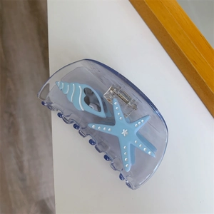 Detail view of a lavender acetate hair claw with blue starfish and seashell ocean motifs