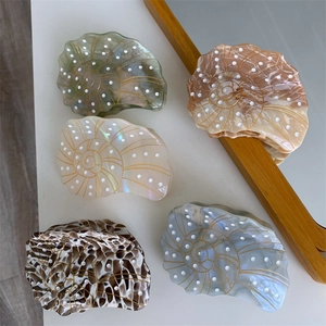 Macro view of shell-shaped acetate hair claws with gold spiral lines and polka dots