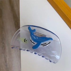 Detailed view of translucent blue whale and small fish patterns on creative acetate hair claw