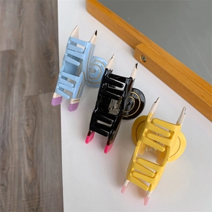 Detailed view of pencil-shaped hair claws in blue, black, and yellow acetate finish