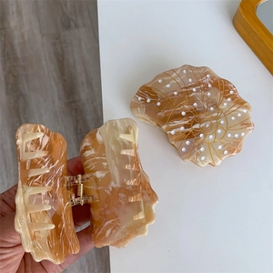 Detail view of acetate seashell hair claw with amber texture and strong metal spring