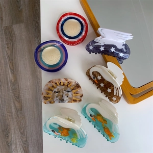 Flat lay of acetate hair claws featuring celestial and swan designs in artistic styles