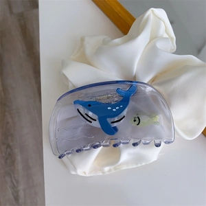 Close-up of a blue acetate hair claw clip with cartoon whale and fish patterns