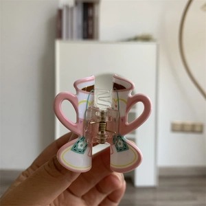 Close-up of pink and white coffee cup shaped acrylic hair claw clip with floral patterns