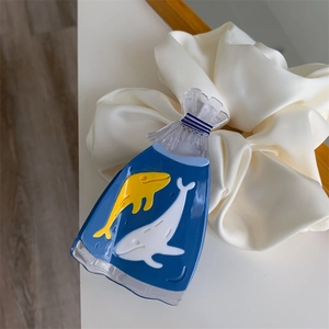 Detail of whale pattern blue acetate hair claw clip resting on cream satin scrunchie