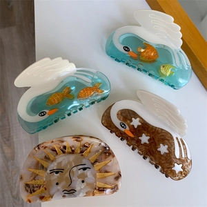 Dreamy acetate hair claws in swan and sun shapes featuring fish and star patterns