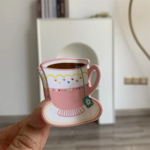 Detailed view of a pink floral tea cup shaped acrylic hair claw clip held in hand