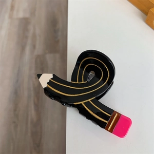 Macro detail of pencil-shaped hair claw clip with gold stripes and pink eraser tip