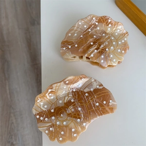 Detailed macro view of shell-shaped amber acetate hair claws with gold spiral patterns