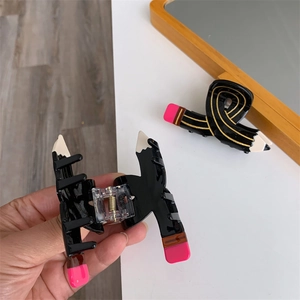 Detail showing creative pencil hair claw clip with gold accents and pink eraser design