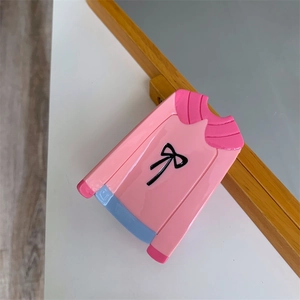 Détail du support téléphone en forme de pull rose avec nœud et finition brillante