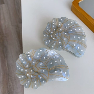 Detailed view of two blue marble acetate shell hair claws with elegant gold spiral patterns