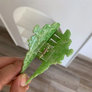 Detail view of acetate green marble vegetable hair claw clip with golden metal spring
