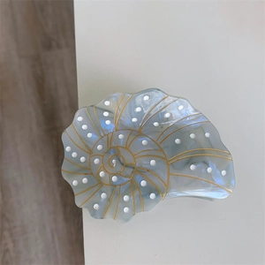 Detail of blue marble cellulose acetate nautilus hair claw with gold lines and dots