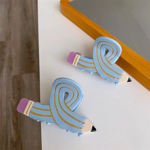 Macro detail of two light blue pencil-shaped hair clips with creative pencil design details
