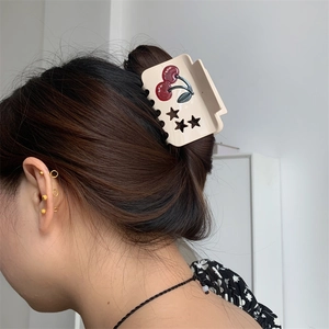 Elegant cream square hair claw clip with red cherry pattern and star cutouts on model