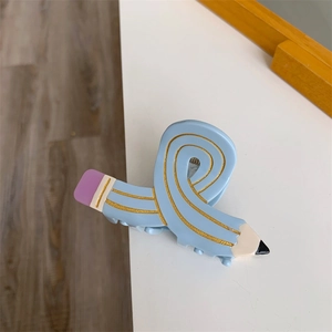 Macro shot of a light blue acetate hair claw clip in a creative pencil shape with gold glitter