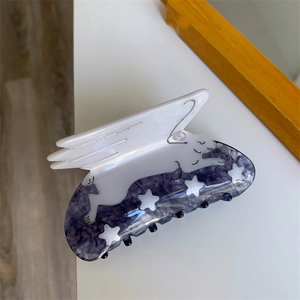 Detail of acetate hair claw clip featuring white flying rabbit and purple marble star pattern