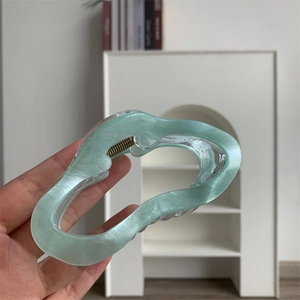Détail d'une pince à cheveux vert menthe ondulée avec finition pailletée semi-transparente
