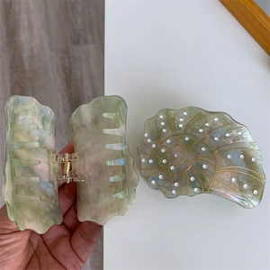 Detail of green marble acetate hair claw clip with shell shape and strong metal spring