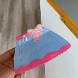 Gros plan d'une pince à cheveux en forme de robe bleue avec nœud rose et bordure