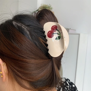 Detailed view of an acetate cherry hair claw clip on a model's elegant updo hairstyle