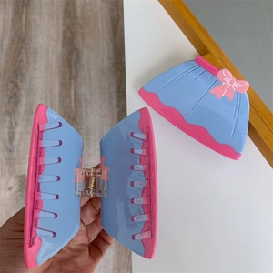 Détail de la pince à cheveux en forme de jupe rose et bleue montrant les dents internes