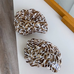 Detail of shell-shaped acetate hair claw clips with tortoiseshell pattern and gold accents