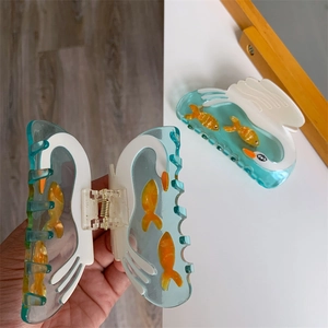 Detail of lake green acetate hair claw clips featuring swan and fish design motifs