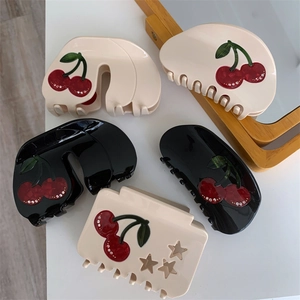 Detailed close-up of cherry patterned hair claws with rhinestones and star cutouts