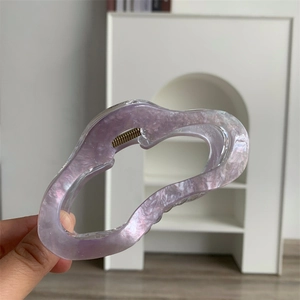 Détail d'une grande pince à cheveux en acrylique lilas avec paillettes et forme ondulée